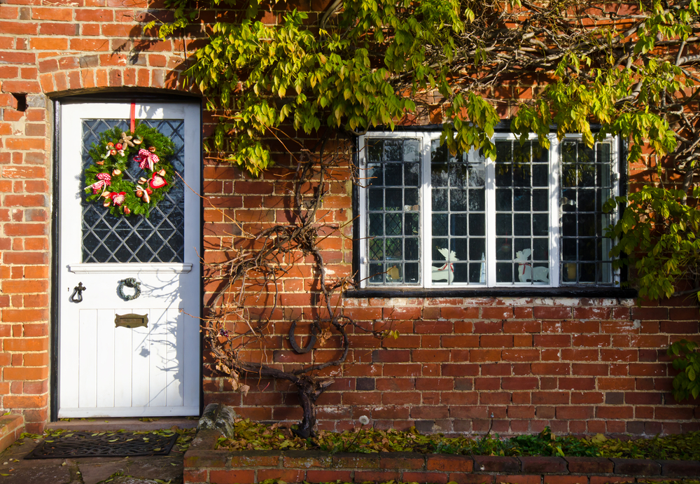 A charming cottage with a white front door adorned with a festive Christmas wreath