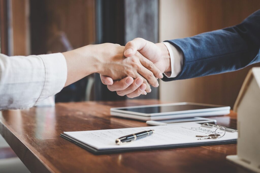 Landlord and tenant shaking hands across a table after completing a rental property inventory and agreeing on the condition of the home