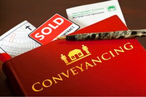 Red conveyancing folder with sold sign, mortgage document, and property map