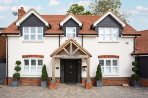 A modern UK detached home with clean brickwork, symmetrical potted plants, and a tidy entrance, showing strong kerb appeal and ideal home presentation.