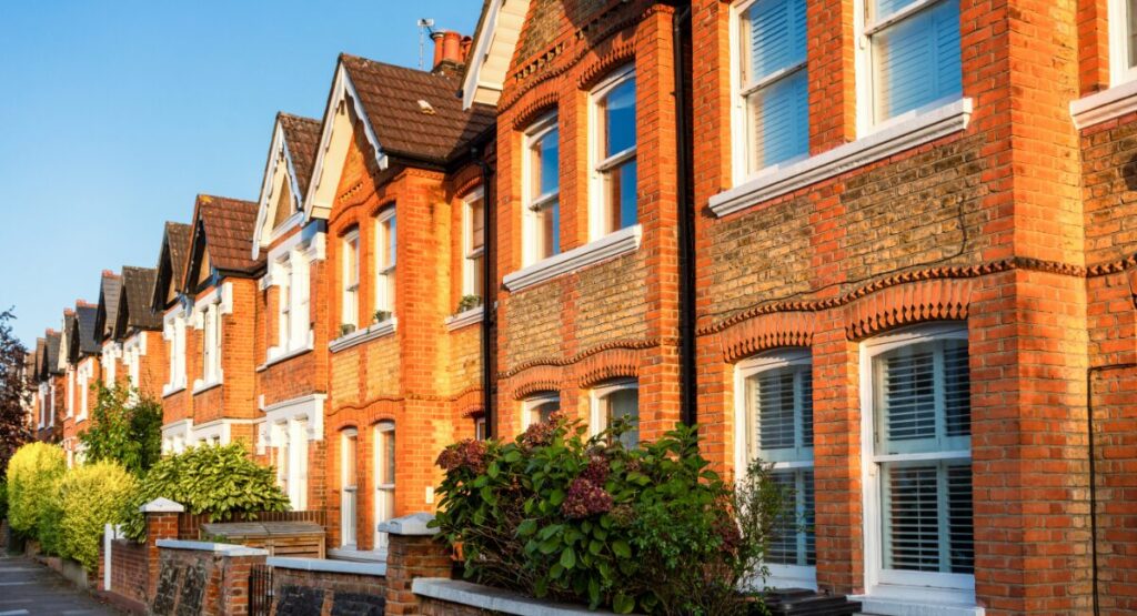 Traditional red-brick terraced houses in the UK with gardens, photographed in bright summer sunlight