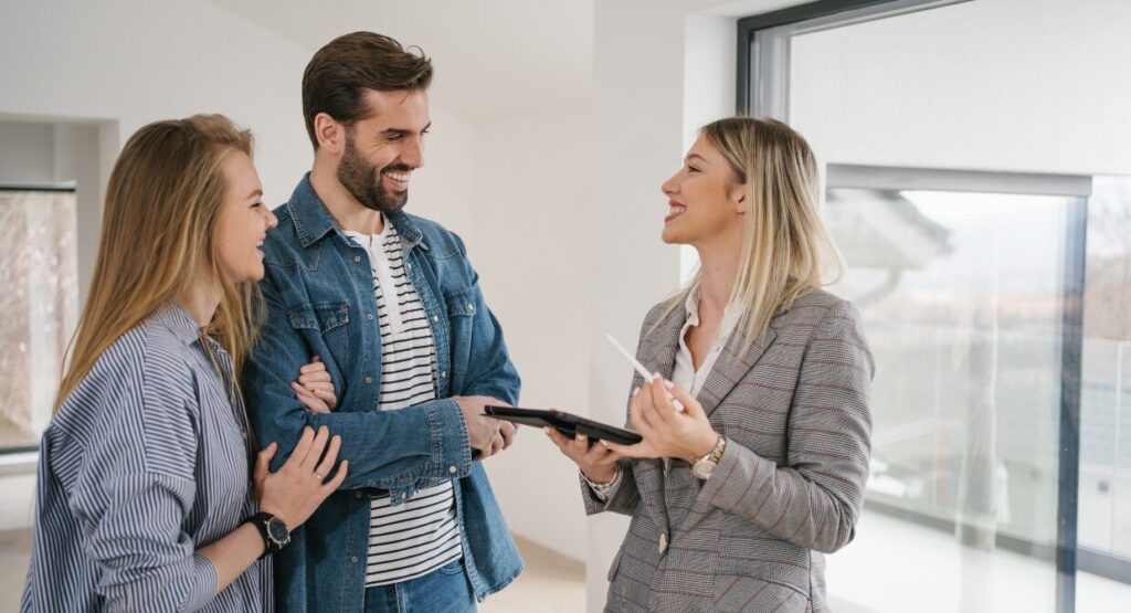 A smiling estate agent talking to a couple during a countryside property viewing, representing what rural buyers are looking for this autumn with Country Properties.