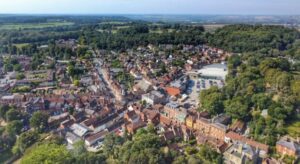 Aerial view of Ampthill showing houses, shops, greenery and surrounding countryside.