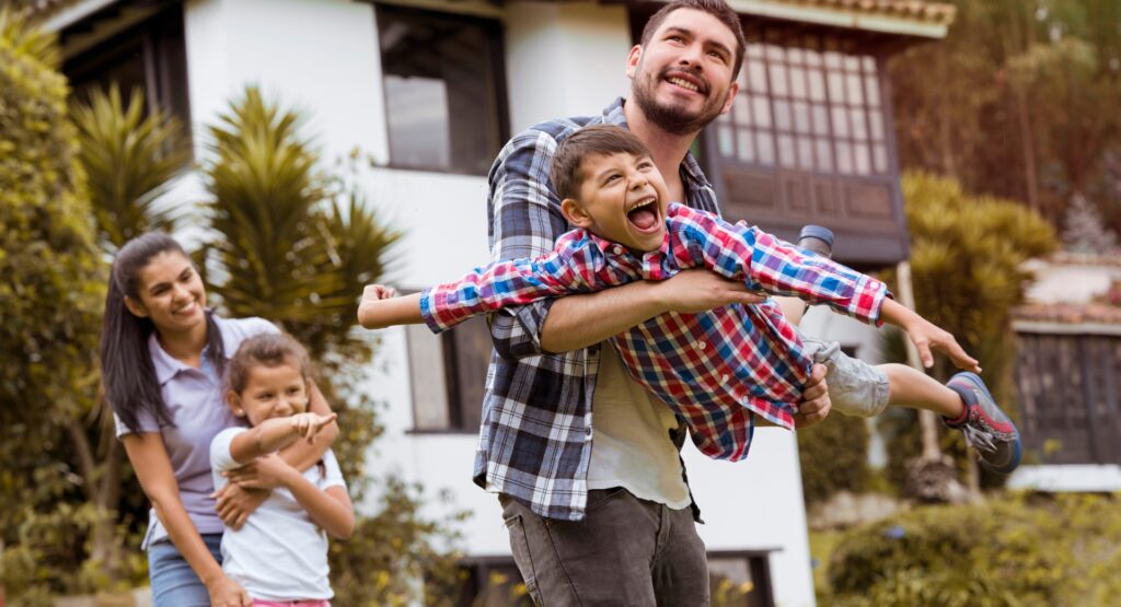 Smiling family playing together outside a rural home, symbolising the benefits of countryside living and the appeal of moving from city to country.