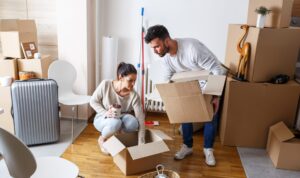 Couple packing boxes in their new home while preparing for moving day, representing the costs buyers face from offer accepted to completion.