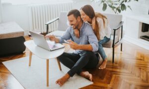 Couple researching rural property and country homes online from their living room.