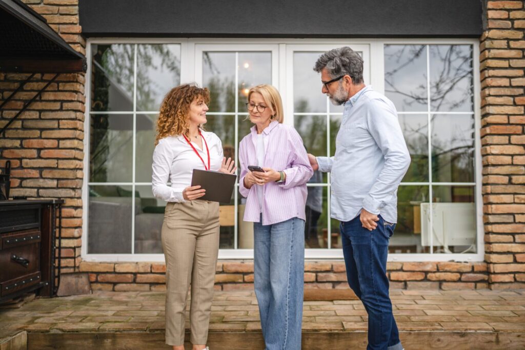 Estate agent discussing a property valuation with homeowners outside a detached house in Hitchin, reflecting renewed seller confidence following mortgage rate stability in 2026