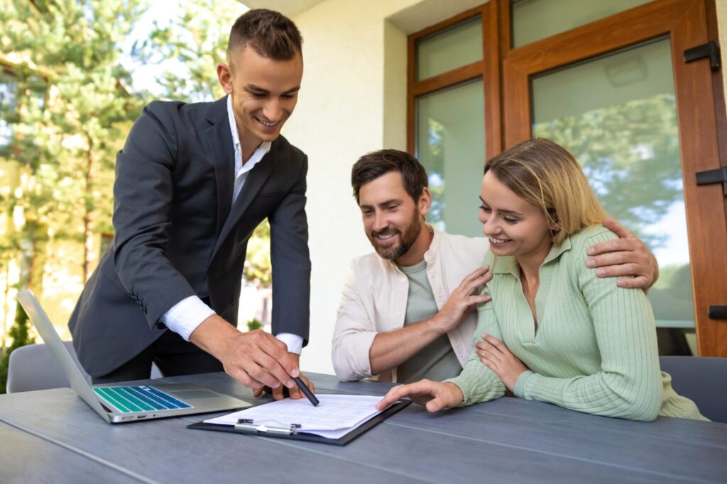 Estate agent reviewing property documents with a couple at a table, representing buyer interest and investment decisions linked to Stevenage’s £1bn regeneration in 2026