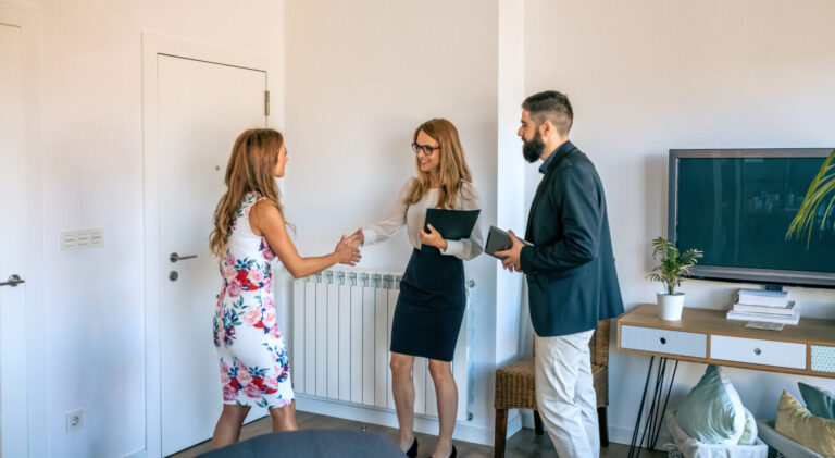 Estate agent shaking hands with a homebuyer during a property viewing in a modern living room