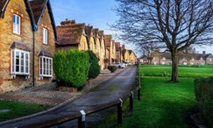 Row of traditional brick houses beside a green open space in a quiet UK village