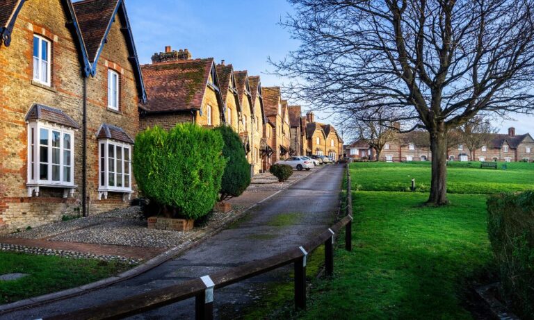 Row of traditional brick houses beside a green open space in a quiet UK village