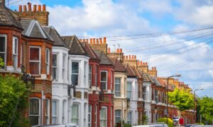 Traditional terraced houses on a residential street in Hitchin with period architecture and parked cars.
