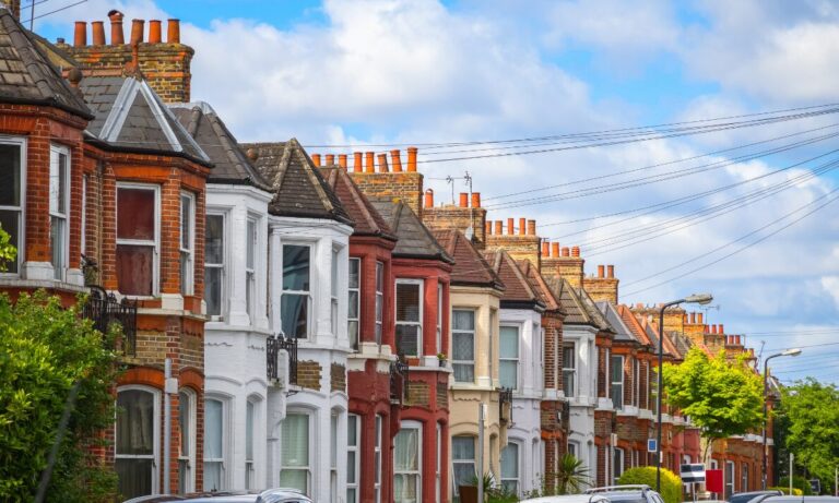 Traditional terraced houses on a residential street in Hitchin with period architecture and parked cars.