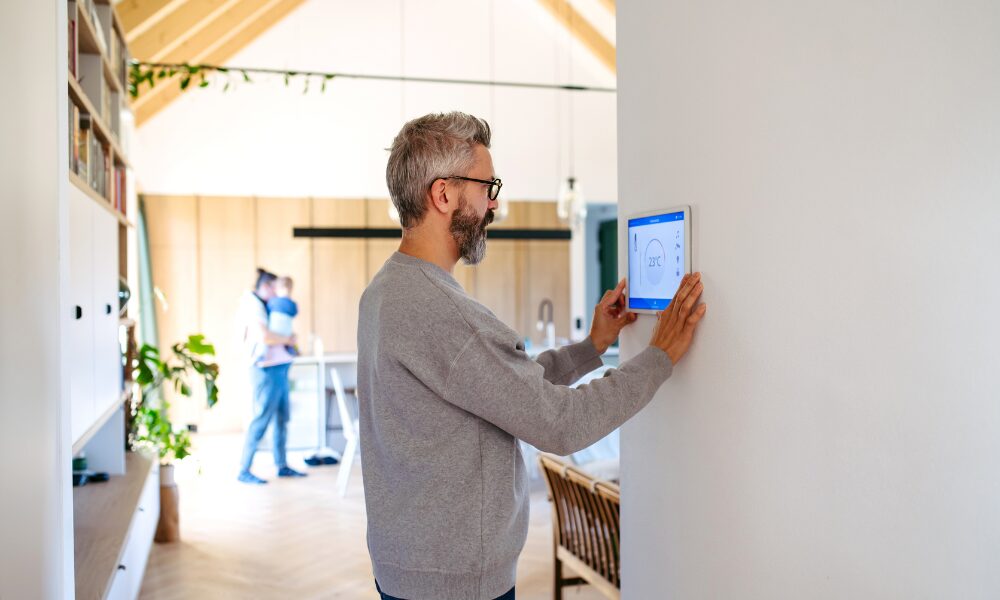 Homeowner adjusting a smart thermostat inside a modernised country home to improve energy efficiency and EPC performance.
