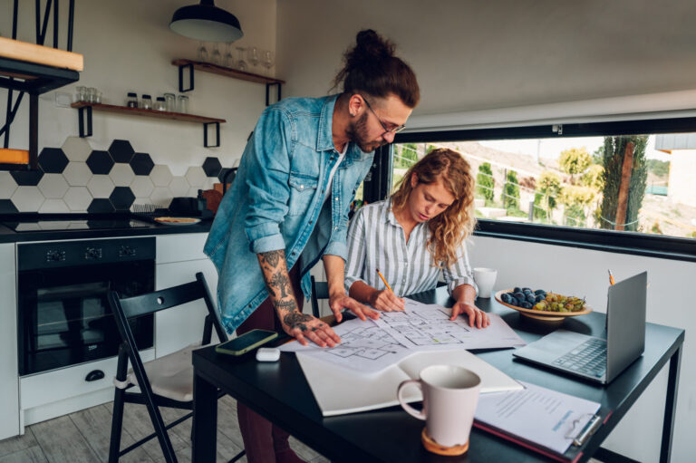 A couple reviewing house plans together at their kitchen table, representing buying a home in Baldock SG7.