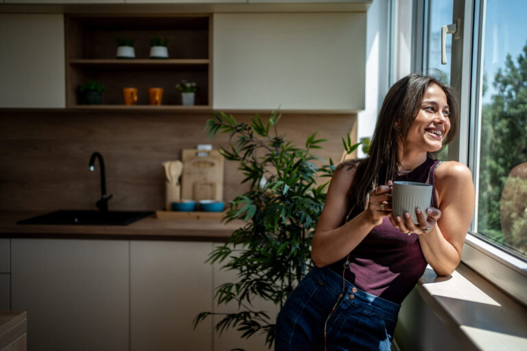 Woman relaxing with a drink in a bright modern home, representing lifestyle and property buying in Gosmore, Hitchin.