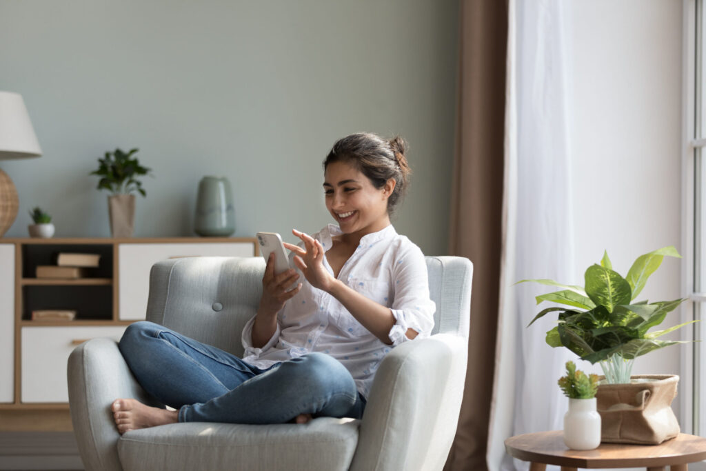Woman using a smartphone while relaxing at home in Preston, Hitchin